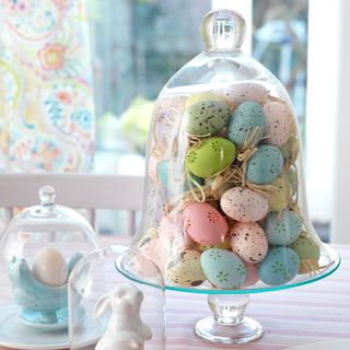 easter decoration with speckled egg glass bell jar and table