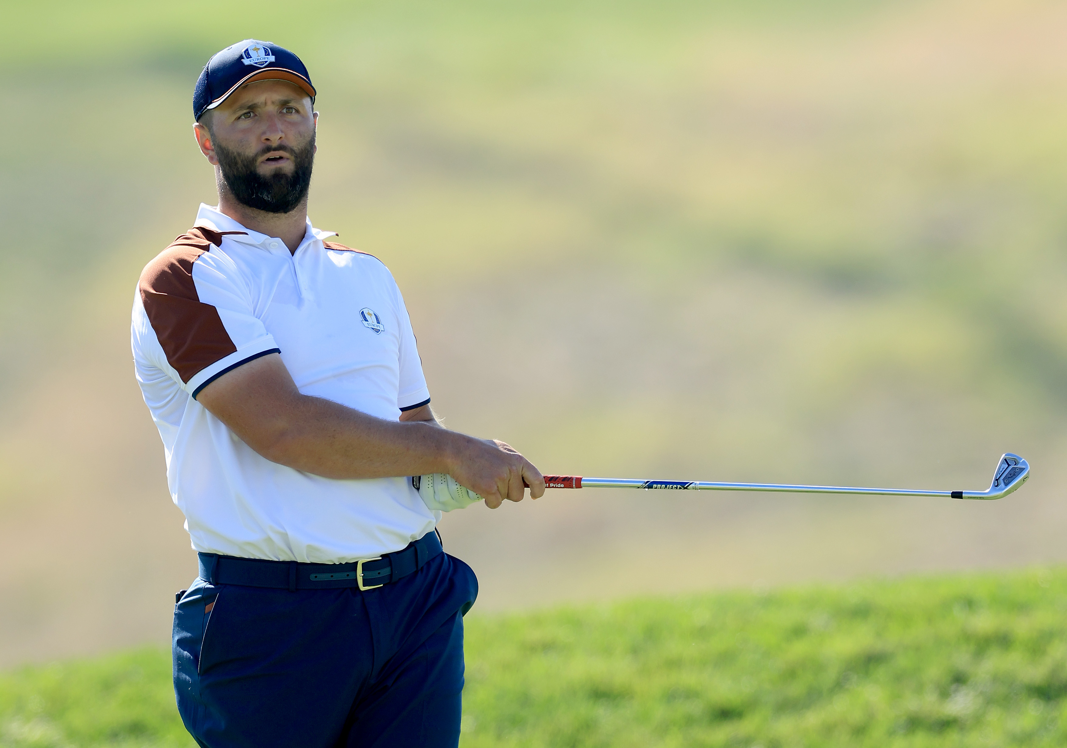 Jon Rahm strikes a golf ball with an iron