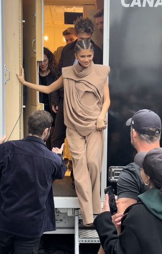 Zendaya wearing a tan architectual top with a pair of tan trousers