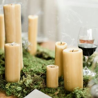 Pillar candles in different sizes position amongst green table setting