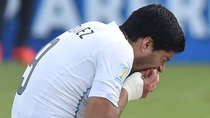 Luis Suarez puts his hand to his mouth after biting Giorgio Chiellini