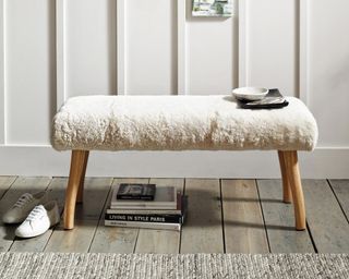 Curly Sheepskin Bench with wooden legs in front of panelled wall