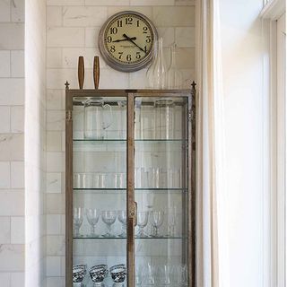 wooden cabinet with glass jars and wall clock