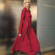 Model wearing a red dress with a matching belt sold at Karen Millen walking past a lift