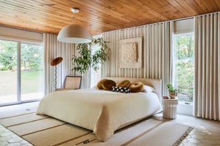 white bedroom with ochre cushions and statement tree by Sarah Sherman Samuel