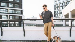 Man checking his phone while walking his dog