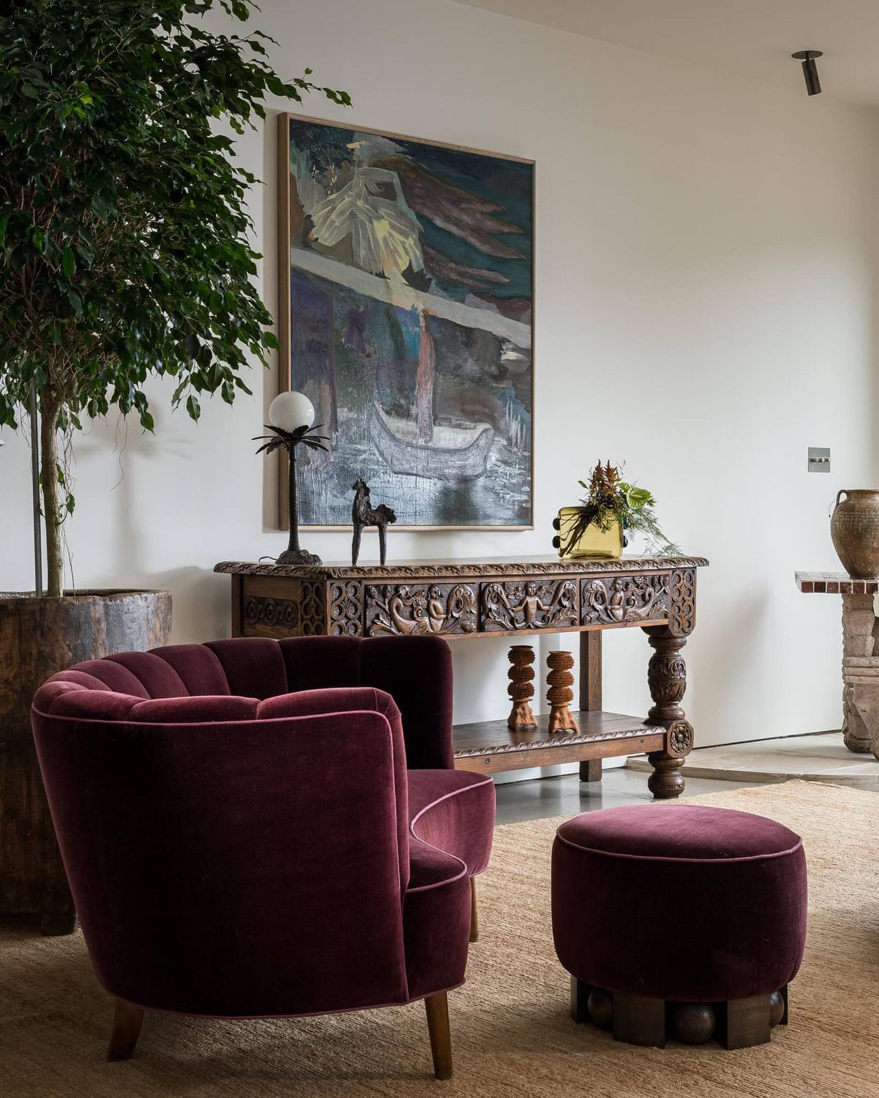 dark burgundy velvet accent chair with a matching ottoman in a earthy-colored living room