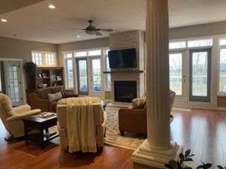 A dated living room with wooden flooring, columns, and two brown sofas