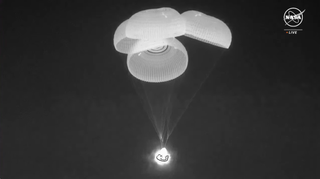 A screenshot showing the sucessfully deployed four parachuettes of the Dragon Capsule as it makes its descent on March 12