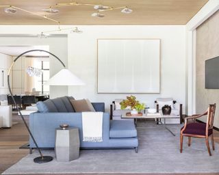 living room with large gray rug, blue corner sofa and wooden chair