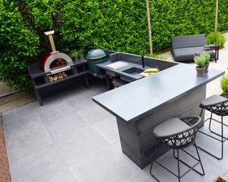 Stone surfaces creating an outdoor kitchen area with pizza oven and big green egg grill