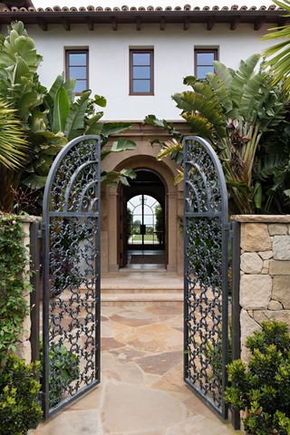 exterior of white rendered home with ornate arched cast iron gate