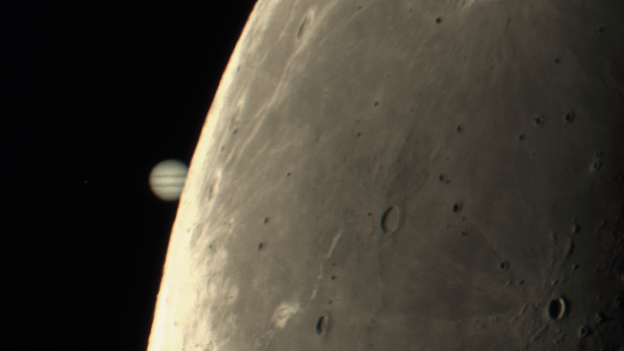 Jupiter is shown partially occulted by the lunar disk in a black sky.