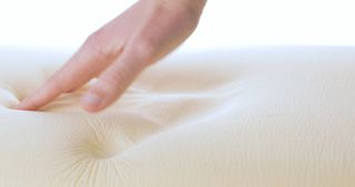 Memory foam mattress with a hand pressing down on it.