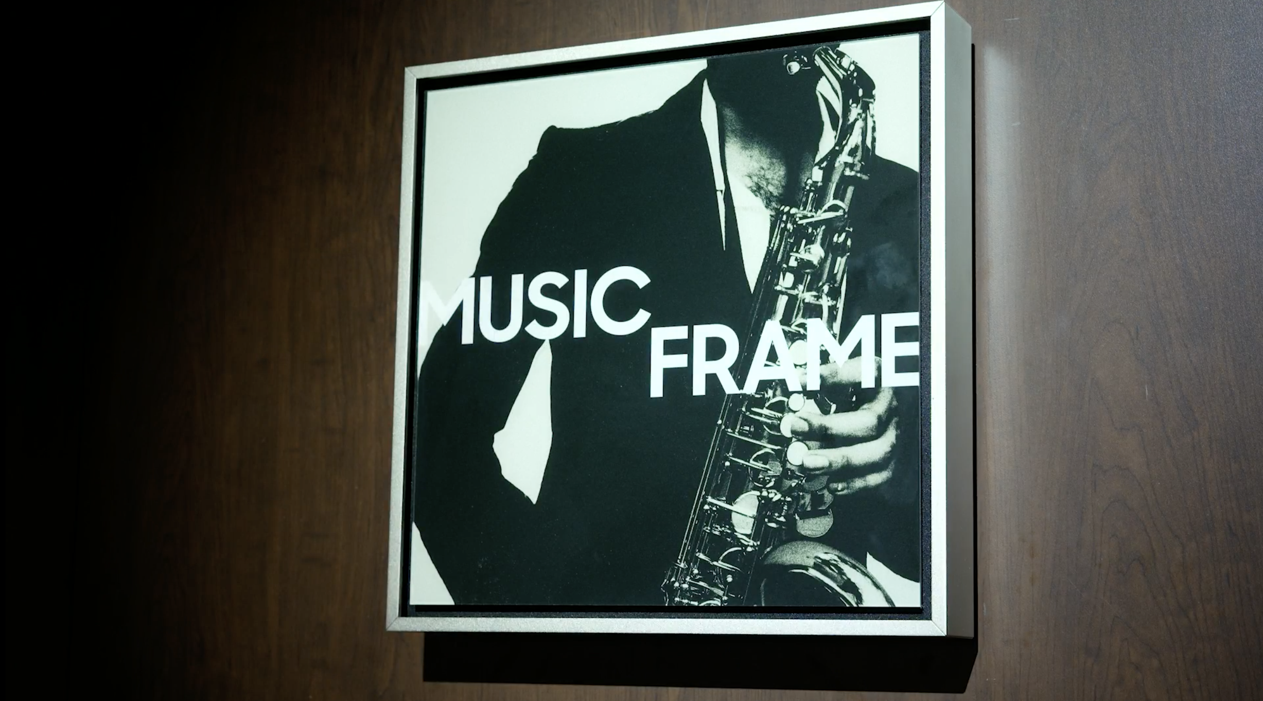 Samsung Music Frame speaker with a saxophone player image, on dark wooden wall