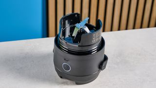 the Nutribullet Flip with a black insulated tumbler and a portable battery-powered blade photographed with a blue background. The tumbler has a carry strap and a sippy lid you can interchange, and an on/off button on the base.