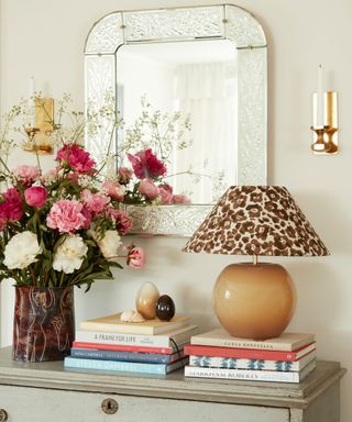 sideboard with mirror and a lamp with a leopard print lampshade and flowers in a vase