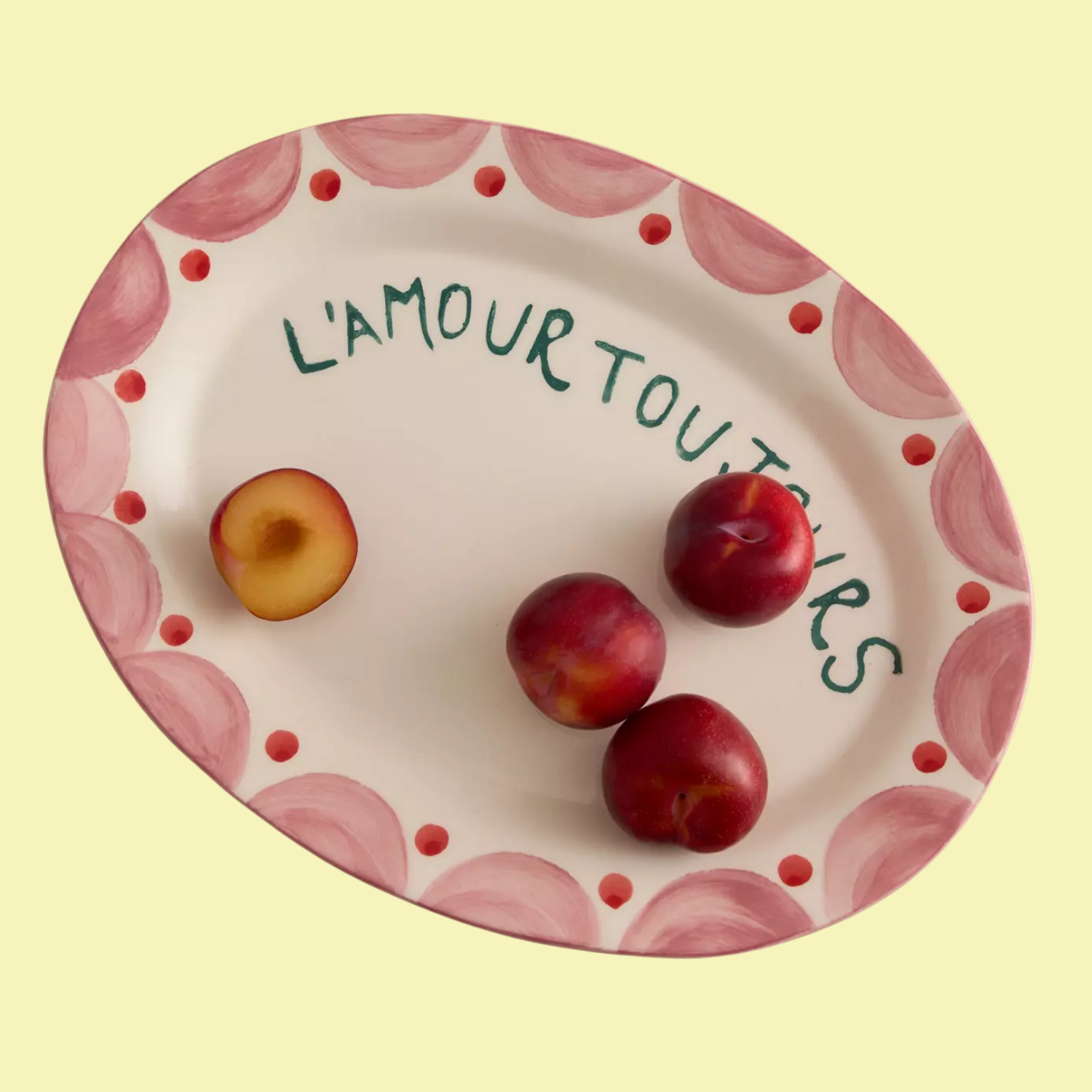 A platter=style plate in pink and red with green writing and peaches