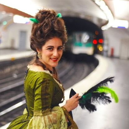 Woman dressed as Marie-Antoinette waiting for a train on the Pairs Metro.