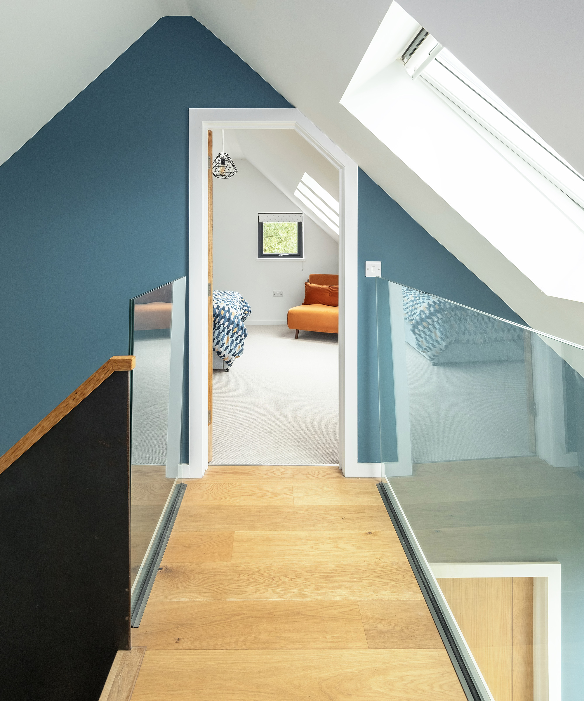 A landing with glass rails leading into a loft bedroom in a self build