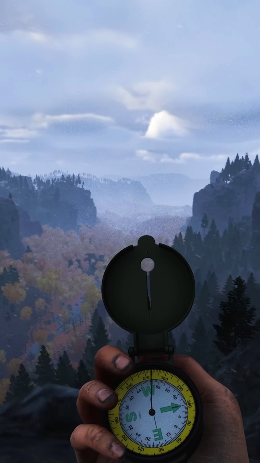 Mountain scenery from Prologue: Go Way back with a player&#039;s hand at the bottom holding a compass