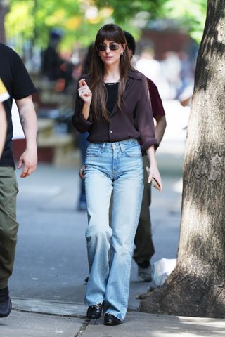 Dakota wears a black button up, jeans, and black gucci loafers.