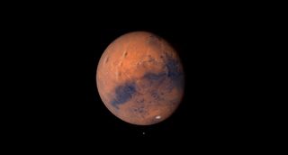a rusty red planet hangs in space.