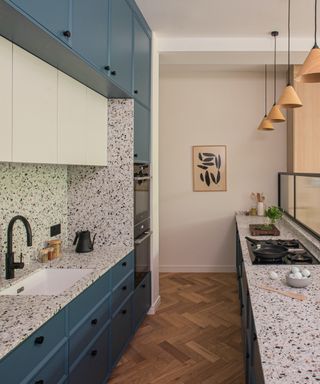 Terrazzo kitchen with blue cabinets and wooden floors