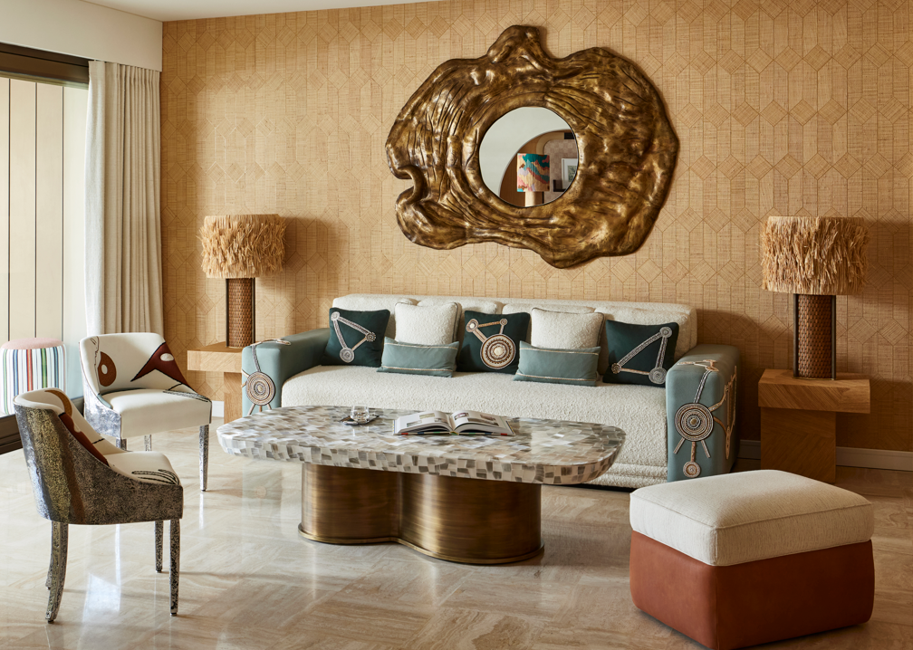 A living room with ochre wallpaper, gold antique mirror and antique gold accessories