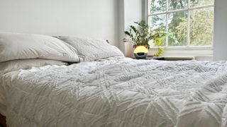 The white weighted blanket on a neatly made bed in a bright bedroom