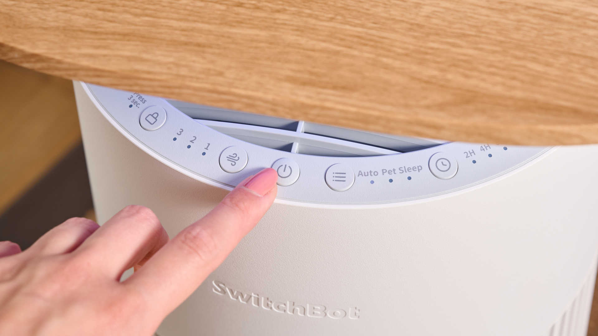 A woman is about to press the power button on the top of the SwitchBot Air Purifier Table.