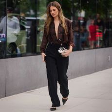 Woman wears striped blouse, black trousers, and pointed-toe heels.