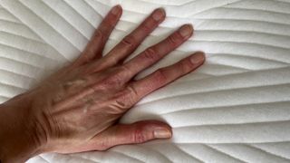 A hand pressing down on the Origin Coolmax Latex Pillow