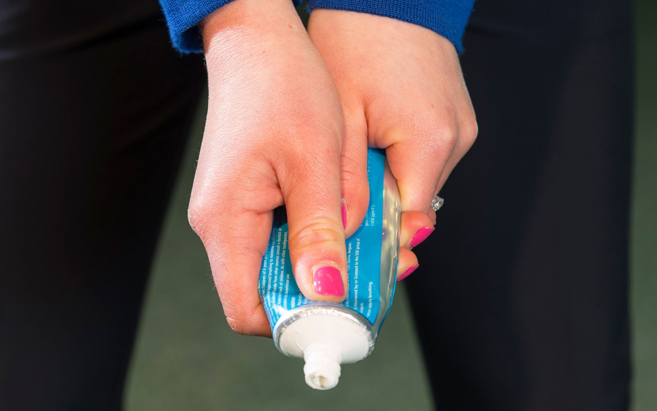 PGA pro Katie Rule holding a toothpaste tube to show how it can help you hone a light grip pressure