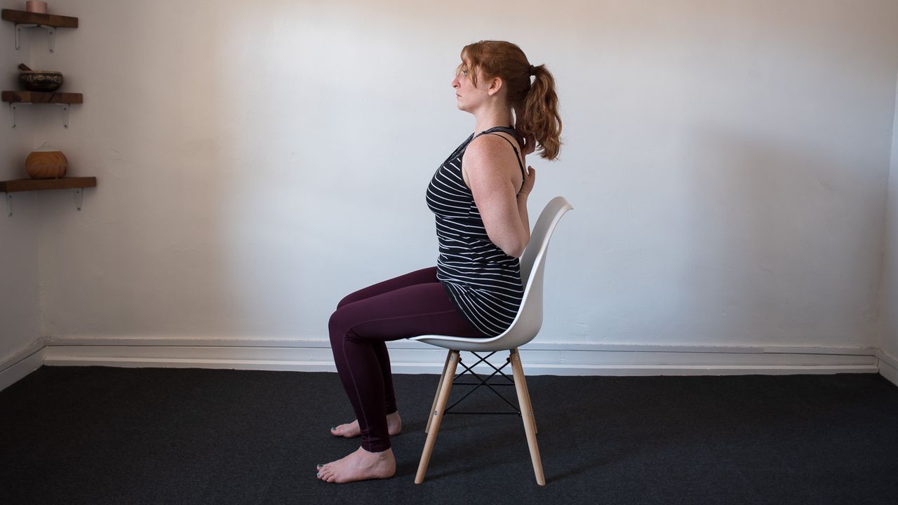desk exercises: seated woman with arms clasped vertically behind her back