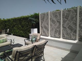 garden screening ideas: white decorative screen in front of hedge