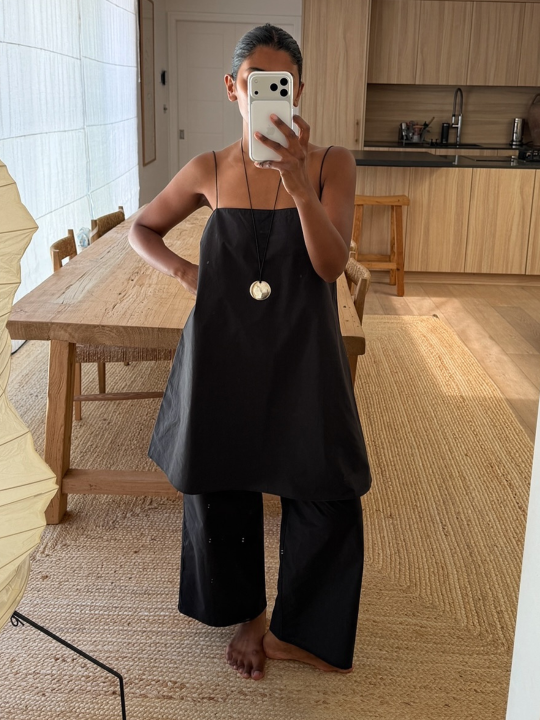 Influencer Monikh wearing a black tunic top, black linen trousers and cord necklace.