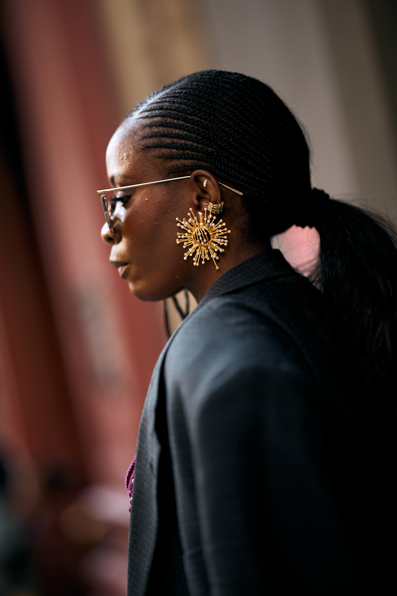 a woman from the side with a black ponytail and gold earrings and sunglasses