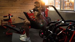 Man performs hack squat exercise in hack squat machine
