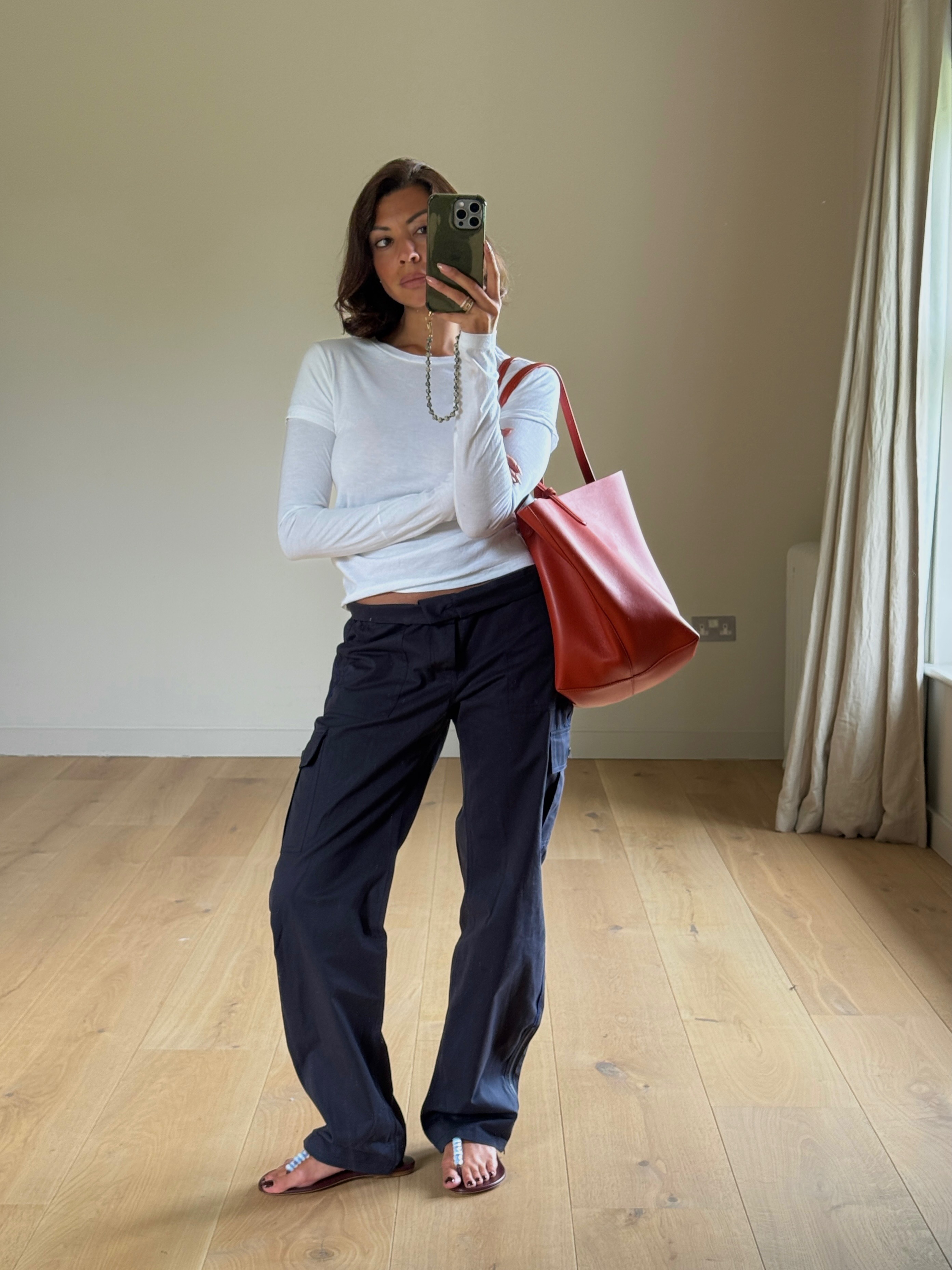 The woman is wearing a white top, navy pants, and beaded sandals