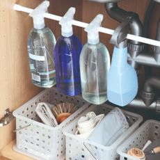 A collection of cleaning products in an under-sink cupboard