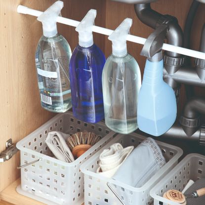 A collection of cleaning products in an under-sink cupboard