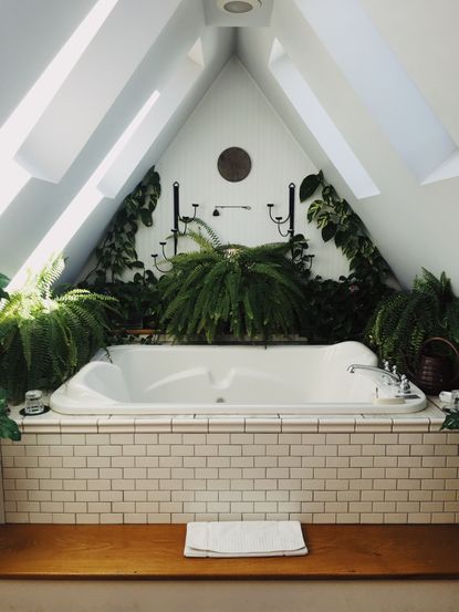 White hot tub with cream metro tiling in alcove surrounded by bathroom plants