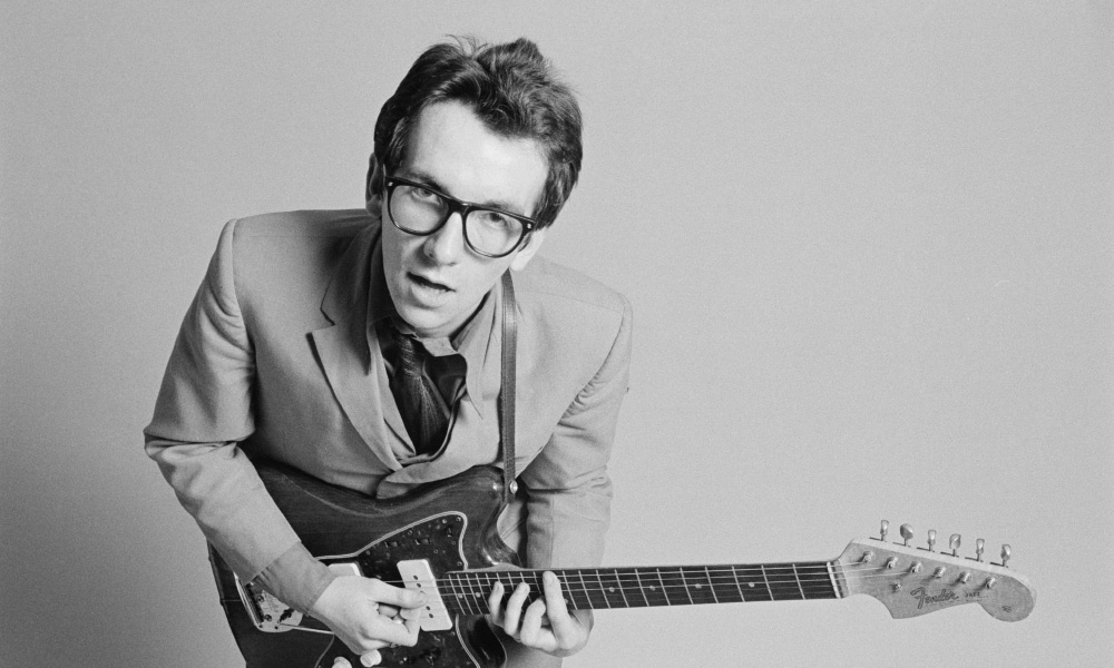 Elvis Costello black and white photo holding a guitar 
