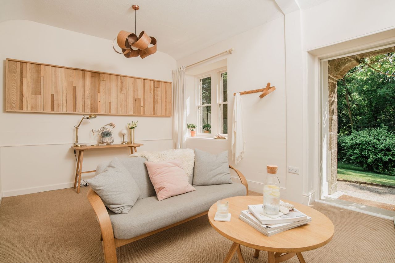 The living room has a curved-timber chandelier and small sofa in an almost completely white timber room