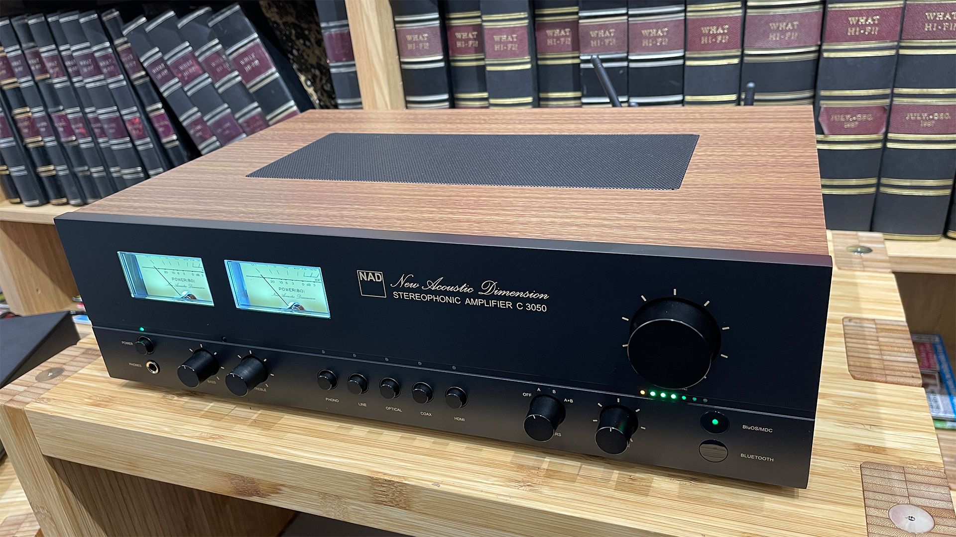 NAD C 3050 (with MDC2 BluOS-D module) streaming amplifier on wooden hi-fi rack in front of bookcase