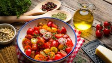 Tomatoes in a bowl with olive oil, wholegrain pasta and herbs, part of the Mediterranean diet