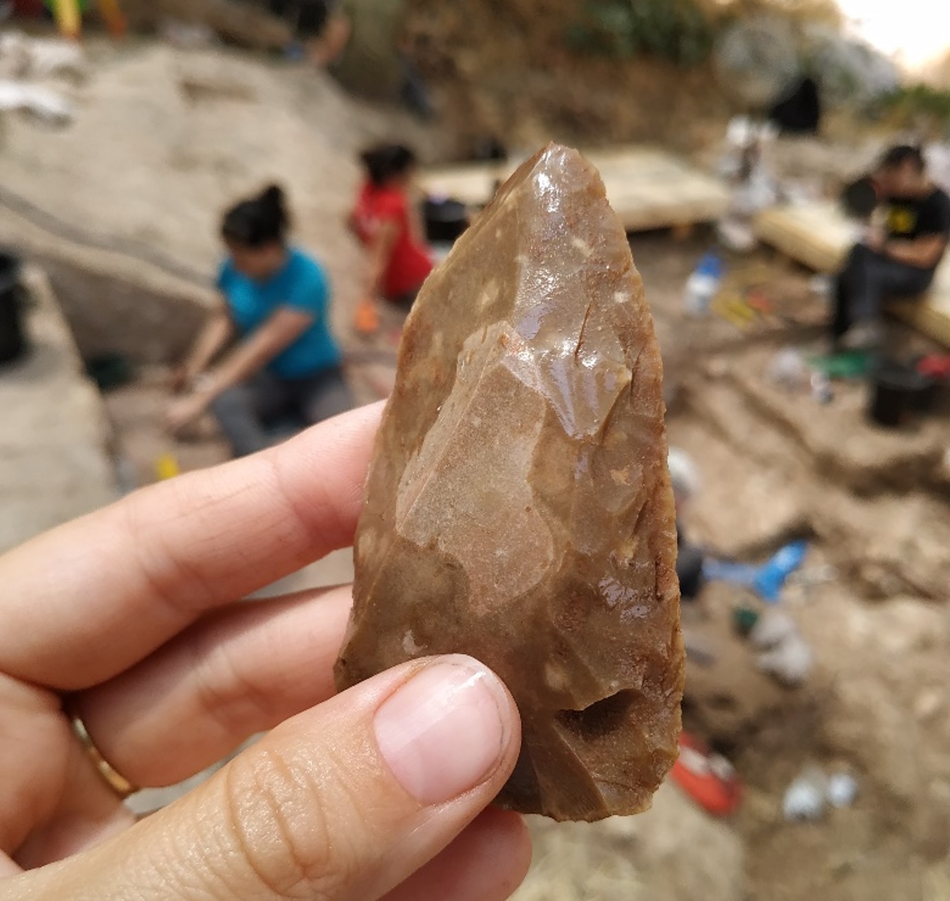 A person holding up an ancient stone tool