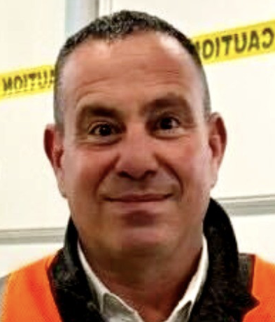 Headshot of a man with close cropped hair and an orange high vis vest on