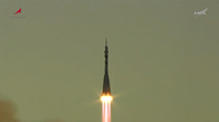 A rocket launches against a chartruce colored sky